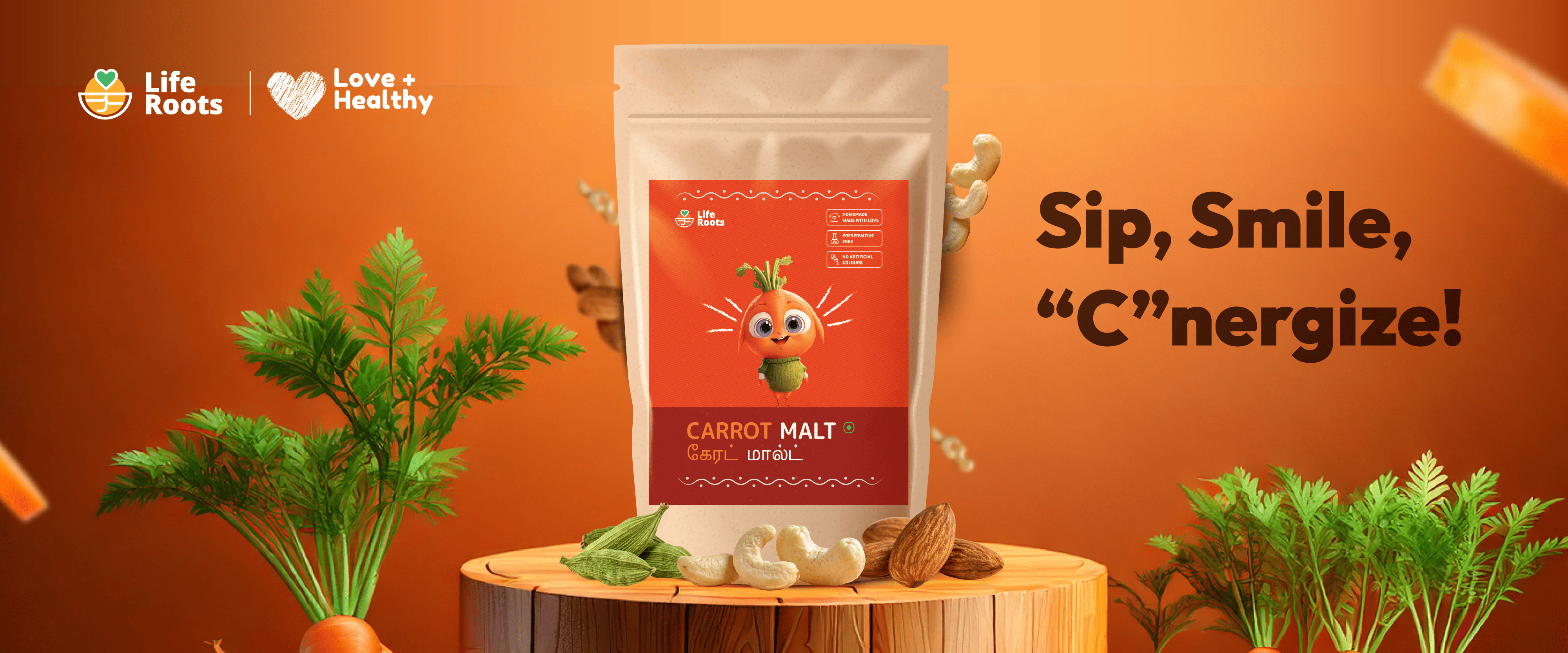 A package of Life Roots Carrot Malt is displayed on a wooden stand with fresh carrots, cashews, and ABC visual branding elements, alongside the text "Sip, Smile, 'C'nergize!" on an orange background.